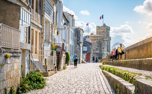 28 July 2021 , La Rochelle France : Beautiful view of the Chain and Saint Nicolas Towers and Sur-Les-Murs medieval street and tourists in La Rochelle historic center France