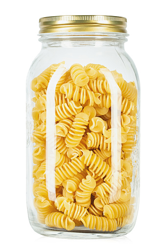 Raw pasta Fusilli in a glass jar  isolated on white background. File contains clipping path.