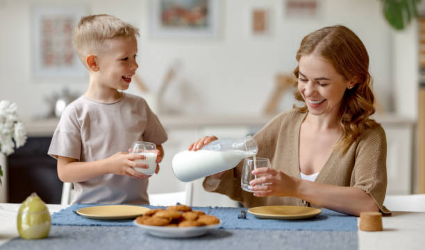 mother pouring milk for son - family mother domestic life food imagens e fotografias de stock