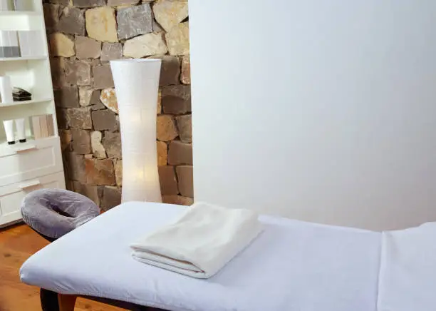 Massage room with massage table and products with stone wall