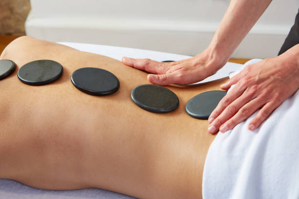 massage aux pierres chaudes chez la femme physiothérapeute du dos - lastone therapy spa treatment massaging massage therapist photos et images de collection