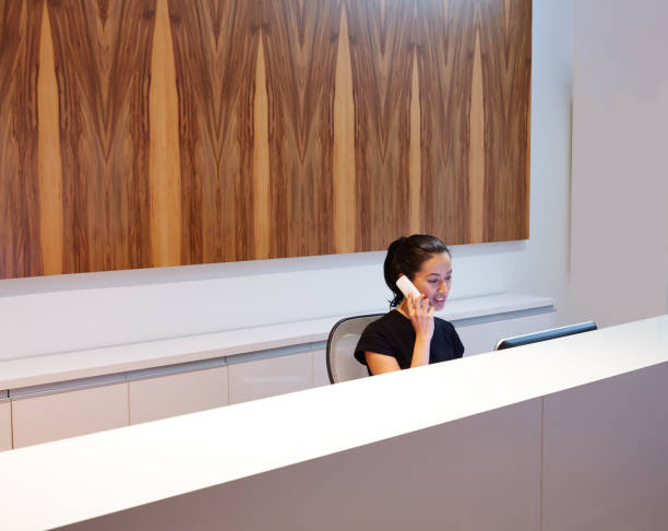 Brunette receptionist young woman in desk Brunette receptionist young woman in desk talking phone receptionist stock pictures, royalty-free photos & images