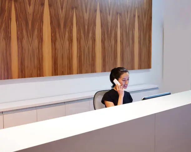 Photo of Brunette receptionist young woman in desk