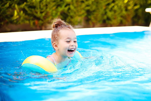 Happy laughing toddler girl having fun in a swimming pool