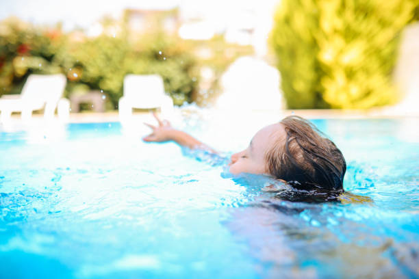 Happy laughing toddler boy having fun in a swimming pool