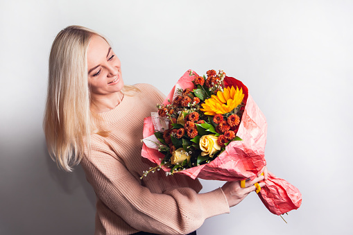 Young woman is holding a large and beautiful autumn bouquet with sunflower, chrysanthemums and roses, with copy space