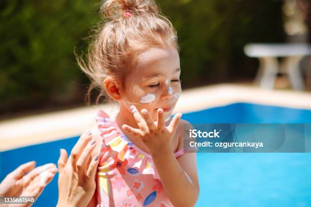 Mother Put Sunblock Cream On Little Daughter Face At Beach Stock Photo - Download Image Now