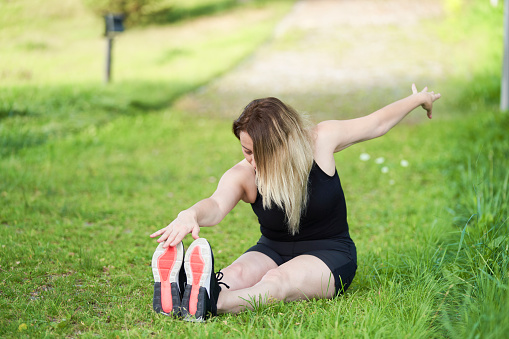 Attractive young woman holding a yoga pose in the park during the day