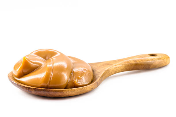 spoon with homemade dulce de leche, condensed cream or pasty caramel, isolated white background. spoon with homemade dulce de leche, condensed cream or pasty caramel, isolated white background. dulce de leche stock pictures, royalty-free photos & images