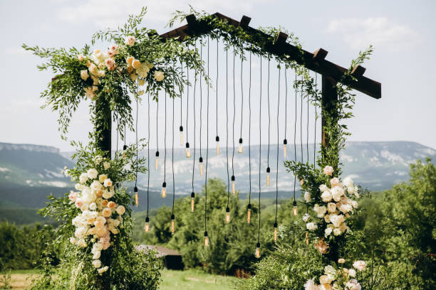 istock Wedding arch on rustuc style with white flowers in park with light bulbs. 1335667980