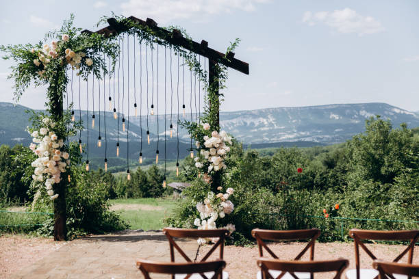 istock Wedding arch on boho style with white flowers in park with light bulbs. 1335669213