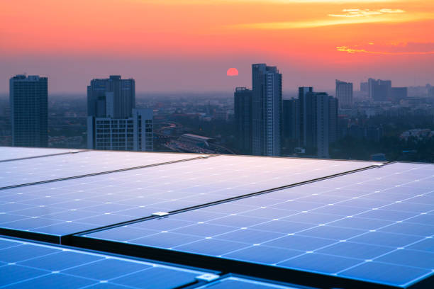 i pannelli solari sui tetti di edifici alti riflettono il tramonto. le città moderne e il traffico sono lo sfondo. energia rinnovabile sostenibile. concetti energetici moderni per l'alloggio e i trasporti - green economy foto e immagini stock