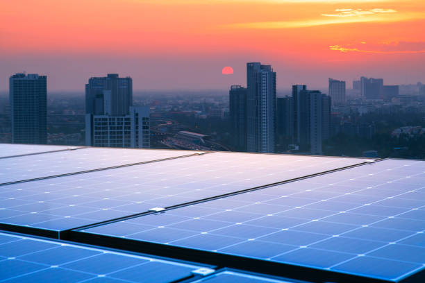 painéis solares nos telhados de edifícios altos refletem o pôr do sol. cidades modernas e o trânsito são os pano de fundo. energia renovável sustentável. conceitos modernos de energia para habitação e transporte - green business - fotografias e filmes do acervo