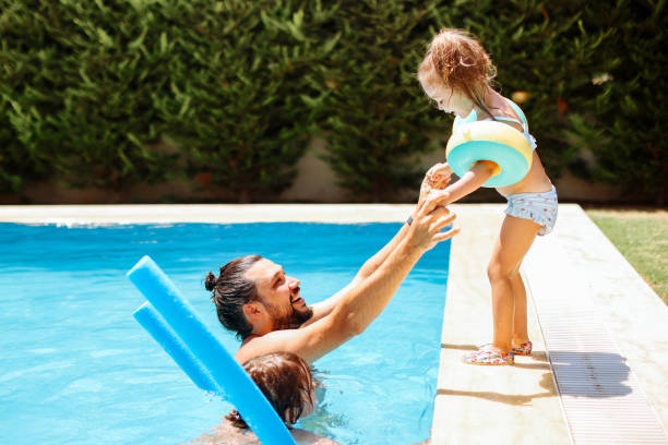 istock Cute little girl having fun with parents in pool 1335672256
