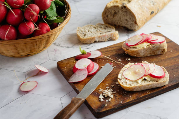 rabanetes fatiados em fatias de pão de baguete de trigo integral com manteiga. - red radish horizontal still life full frame - fotografias e filmes do acervo