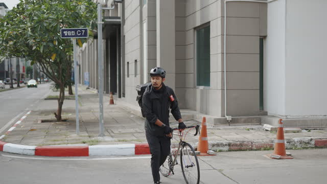 Asian courier man walking and towing bicycle