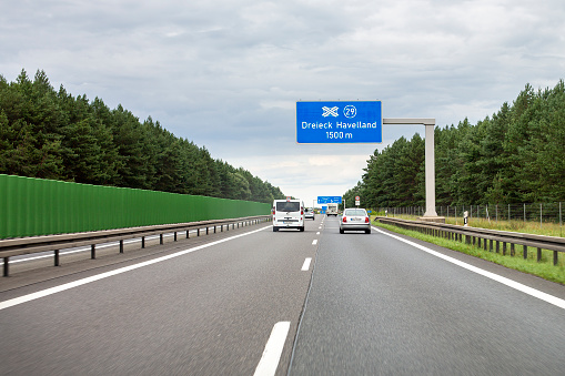 Dreieck Havelland, Germany - August 08, 2021: Traffic on german Autobahn A10 (Berliner Ring) nearby Potsdam in Brandenburg. The Bundesautobahn 10 (abbreviated as BAB 10 or A 10 or Berliner Ring) is an orbital motorway around the German capital city of Berlin. Dreieck Havelland forms the connection to the autobahn A24 (Rostock-Hamburg-Berlin). Some road users in the background.