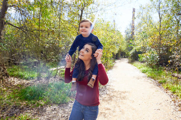 istock kid boy sit on mother shoulders walking park 1335678758