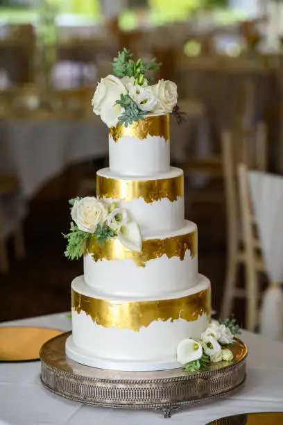 Four tier wedding cake with gold leaf and fresh flowers