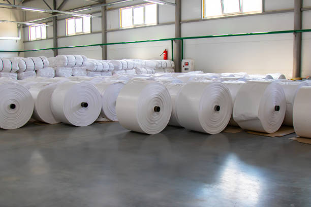 raw materials warehouse. many large coils of finished propylene hose made of woven thread for making industrial bags. polypropylene rolls for packaging. - propylene imagens e fotografias de stock