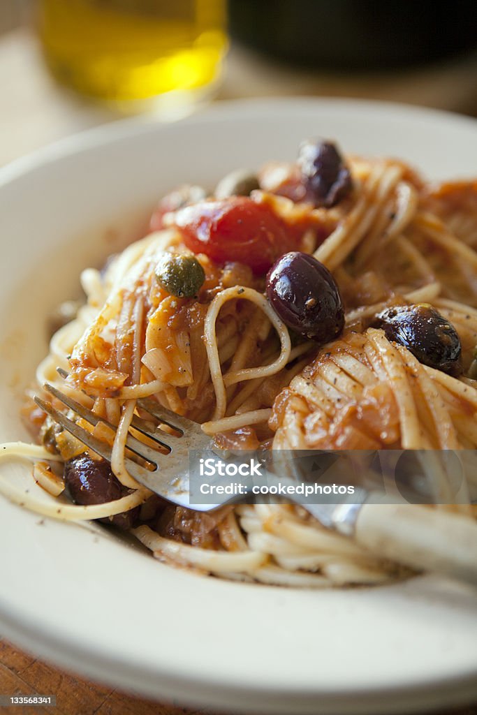 Puttanesca Pasta Puttanesca pasta, a traditional Italian spaghetti dish containing anchovy, garlic, capers, olives and tomatoes. Olive - Fruit Stock Photo