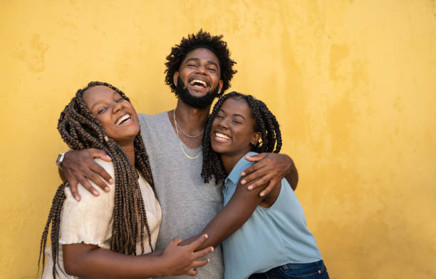 umarmung von afro-menschen gelber hintergrund - youth culture women human face portrait stock-fotos und bilder