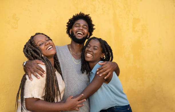 abrazando a la gente afro de fondo amarillo - afrodescendiente fotografías e imágenes de stock