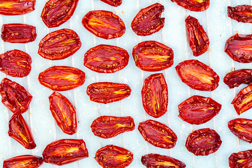 Tomato halves sprinkled with salt are dried on a sheet of parchment. Top view, flat lay. Concept of cooking homemade canned food.