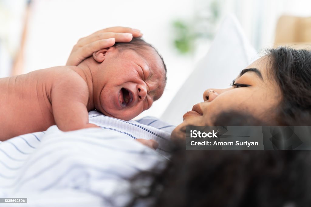 Newborn baby crying on mother's. Mother take care her African American infant on hands with kindness. family, love, happy and new life concept Newborn Stock Photo
