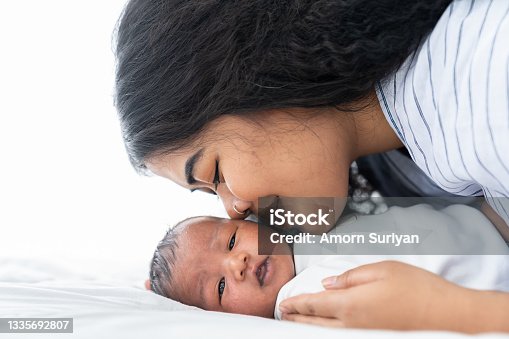 istock Mother kissing her newborn baby on the bed. Closeup of mom and infant baby 1335692807