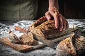 Male hands cutting Sourdough bread slices wholegrain homemade German style on cutting board