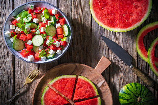 Healthy vegetarian watermelon salad bowl with feta cheese, cucumber and parsley on rustic wooden background, Mediterranean diet
