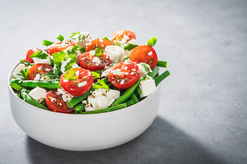 Healthy vegetarian salad bowl with cherry tomatoes, green beans, feta cheese and parsley, Mediterranean diet
