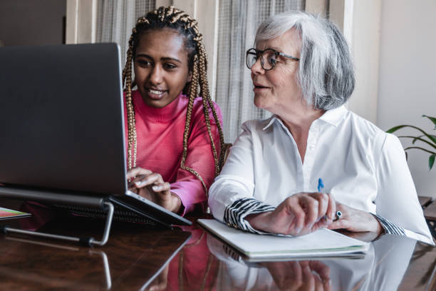istock Multiracial senior and young woman using laptop computer at home - Focus on right face 1335697130