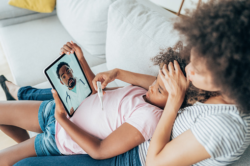 Mother and daughter consulting with their doctor over a video call on their digital tablet.