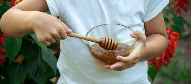 istock child eats honey in the garden. 1335707432