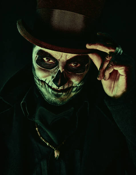 Young man in image of Baron Samedi, the Voodoo deity. Baron Saturday in black coat and top hat, close-up portrait. Day of the Dead (and Halloween) theme A young man in image of Baron Samedi, the Voodoo deity. Baron Saturday in black coat and top hat, close-up portrait. Day of the Dead (and Halloween) theme muerte stock pictures, royalty-free photos & images