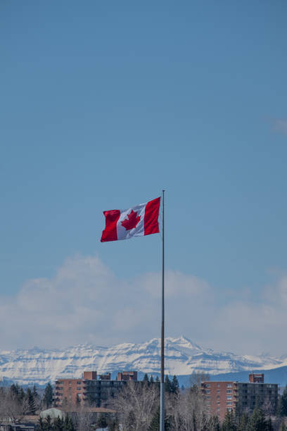 istock Canada flag flying in the wind with mountains in distance 1335712633