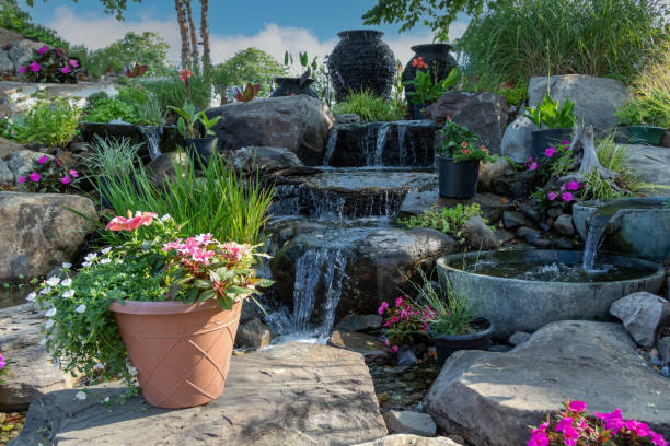 istock Waterscape fountain urns create a beautiful tranquil backyard oasis surrounded by bright pink and red flowers and ornamental grasses 1335712708
