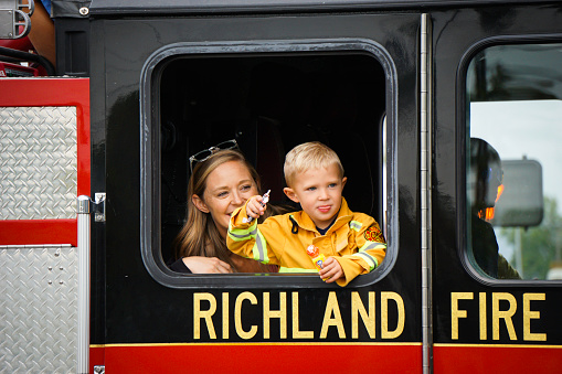 Kennewick, WA - August 21, 2021: Young child and woman ride in fire truck during parade