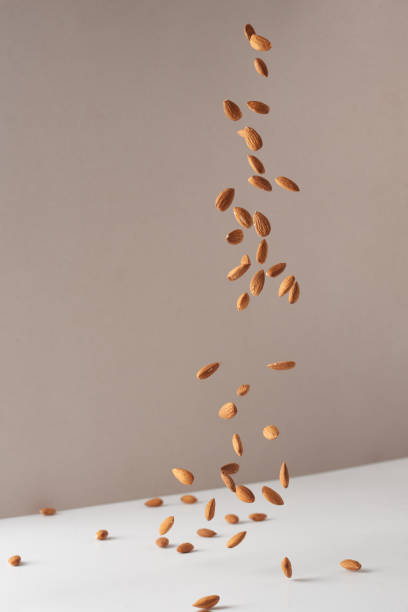 flying almond nuts. fresh raw almonds fall on a white background. - healthy eating macro close up nut imagens e fotografias de stock