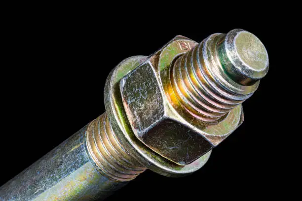 Photo of Hexagonal nut and washer on metal galvanized wedge expansion anchor bolt end on a black background