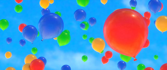 Close up on sparse colorful balloons flying up on a blue sky. Wide horizontal composition.