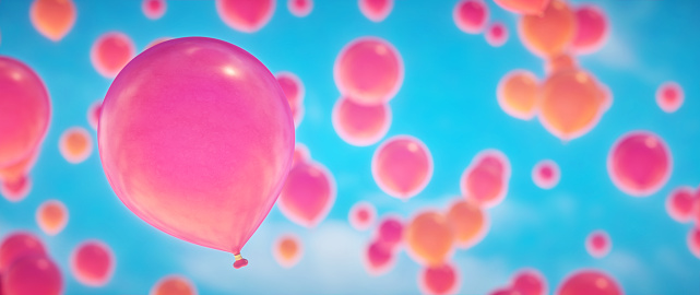 Close up selective focus on pink balloons flying up on a clear sky. Wide horizontal composition.