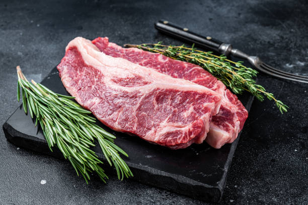 istock Raw Striploin steak or New York steak beef meat cut. Black background. Top view 1335720913