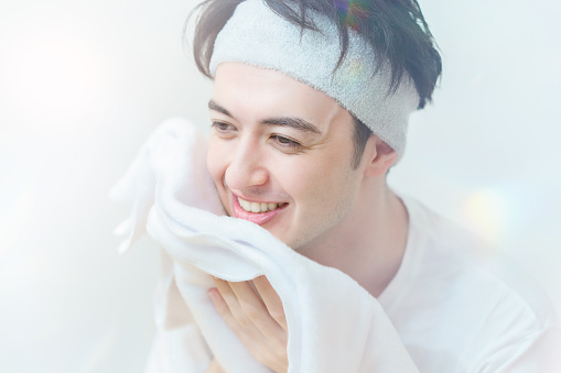 Asian young man wiping his face with a towel