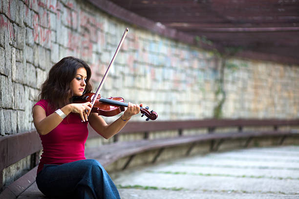 Young Caucasian man playing violin outdoor for money.