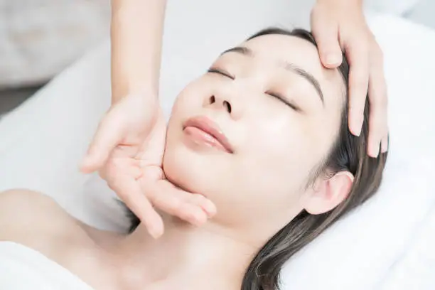 Asian young woman whose head is massaged at an esthetic salon
