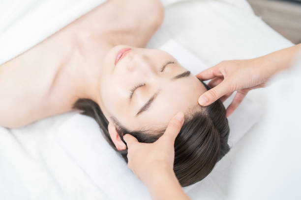 une jeune femme dont la tête est massée dans un salon esthétique - head massage photos et images de collection