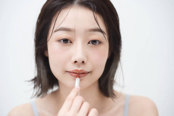 istock Young woman applying lipstick to her lips 1335743289